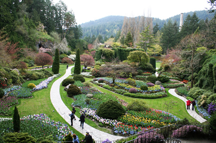 looking down at a lush garden with pathways, trees and colourful flowers