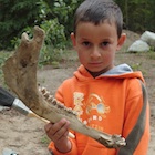 Little boy holding a jaw bone that he helped dig. 