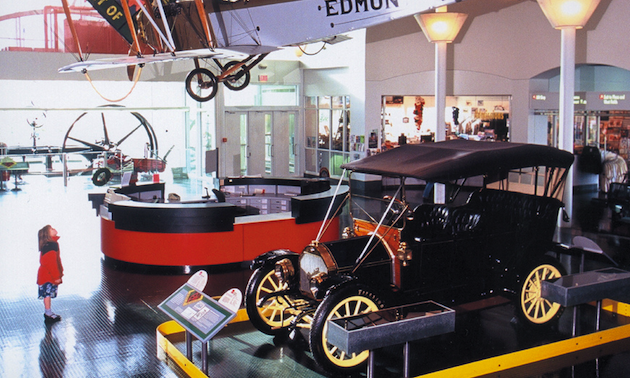 little girl looking up at a plane in a museum, vintage car