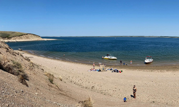 Lake Diefenbaker, with a sandy beach and people sunbathing in swimsuits