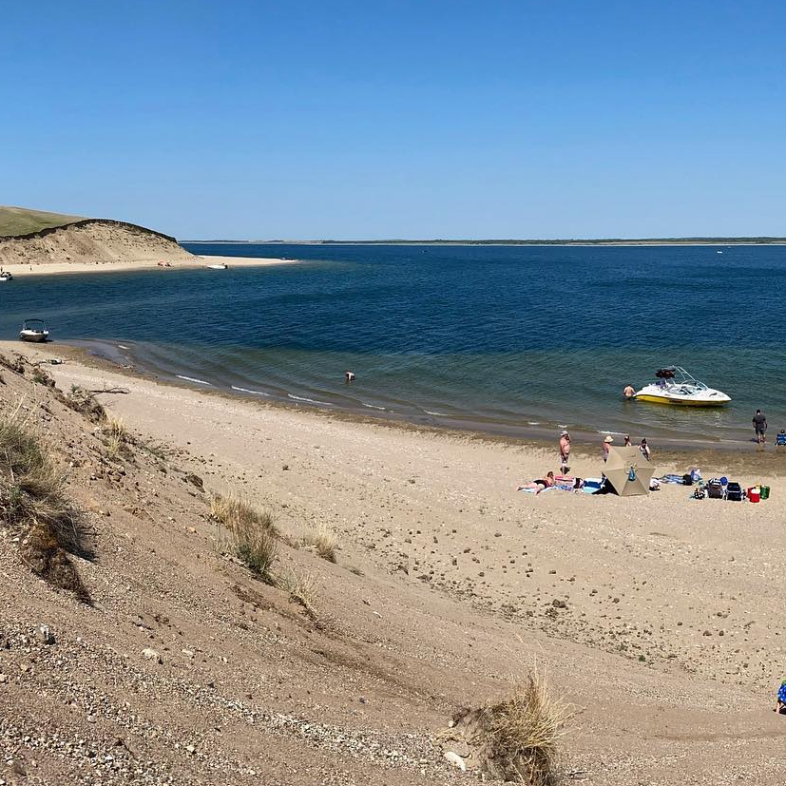 Lake Diefenbaker, with a sandy beach and people sunbathing in swimsuits