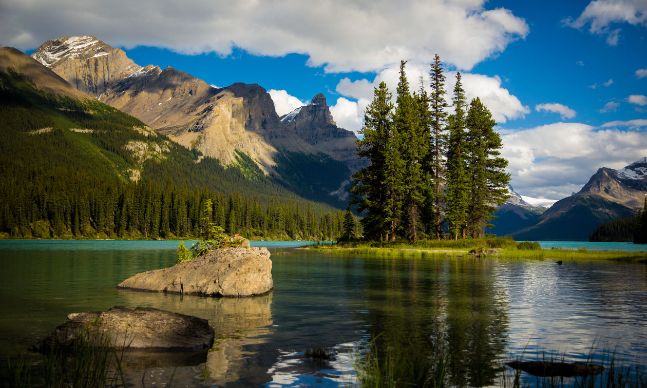 Spirit Island lit up by the sun from the shore on Maligne Lake.