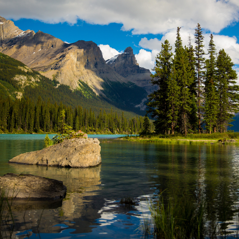 Spirit Island lit up by the sun from the shore on Maligne Lake. 