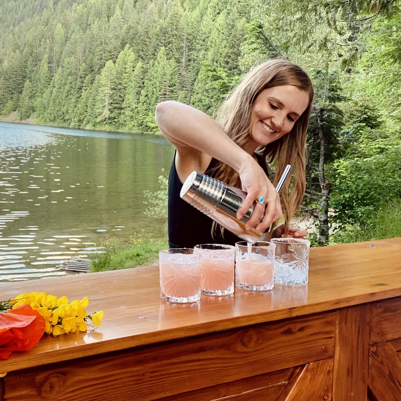 owner of Vintage Pour Mobile Bar pouring a drink with the trees and lake in background