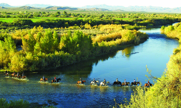 people on horseback riding through a river