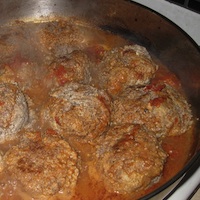 Meatballs simmering in a tomato sauce.