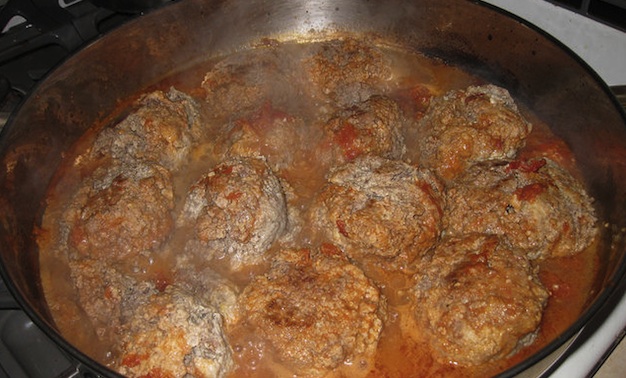 Meatballs simmering in a tomato sauce.