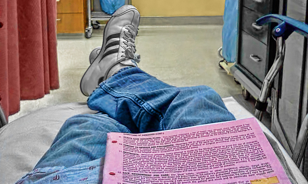 person laying in a hospital bed, with insurance papers on their lap