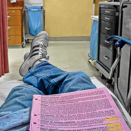 person laying in a hospital bed, with insurance papers on their lap