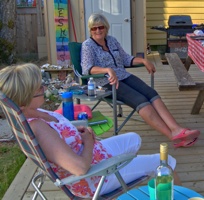 3 friends sitting in lawn chairs on a deck in front of an RV.