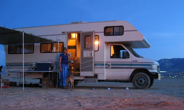RV at an RV park with a smiling lady and her dog standing in front