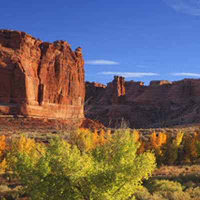 Picture of Moab, Utah with towering red rock and scrub-brush. 