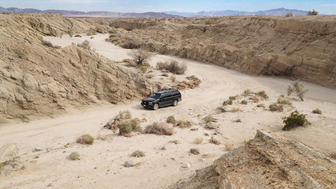 A four-wheel-drive vehicle is parked in a dry wash near the Arroyo Tapiado mud caves.