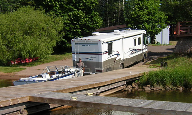 Picture of RV backing boat down a boat ramp. 