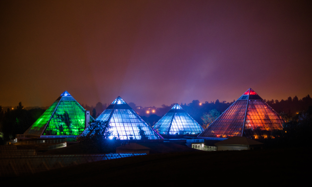 The pyramid shaped conservatory buildings at night, all lit up 