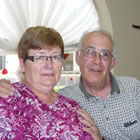 Photo of an older couple sitting on the couch together. 