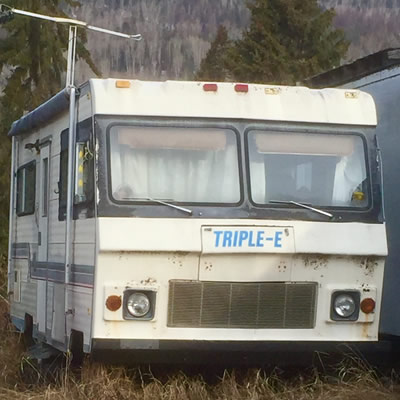 An old Triple E motorhome parked in tall grass. 