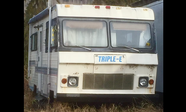 An old Triple E motorhome parked in tall grass. 