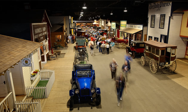 Old cars and wagons are lined up inside the Western Development Museum. 