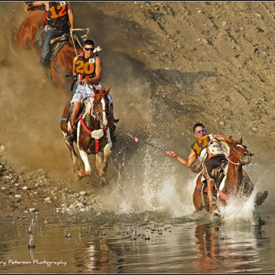 Picture of horses and riders coming down a steep bank beside a river. 