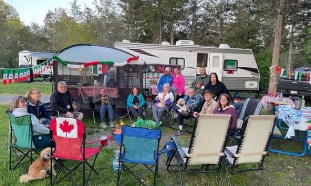 People gathered on lawn chairs by an RV