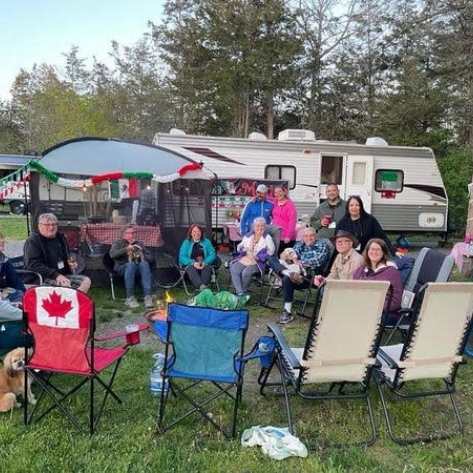 People gathered on lawn chairs by an RV