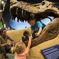 Two children playing on a dinosaur display at the Exploration Place in Prince George, B.C.