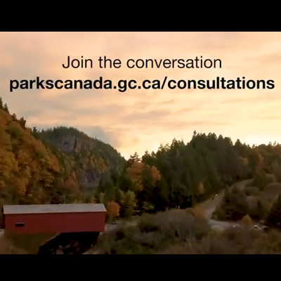 Video still from Parks Canada website, showing covered bridge and forest. 