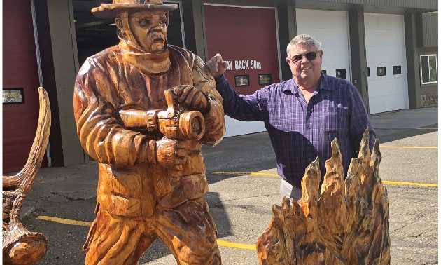Man standing beside a carved firefighter