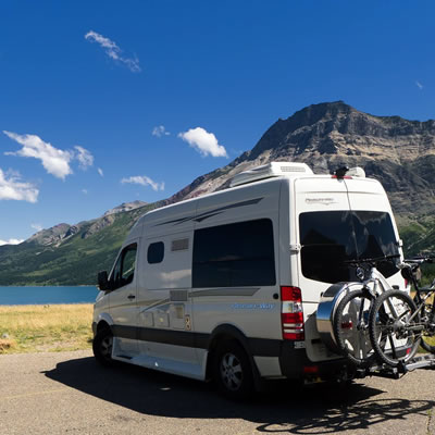 A Pleasure-Way van, parked in front of a lake. 