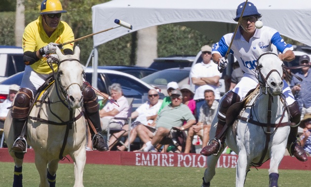 2 riders, one in yellow, the other in blue, playing polo at the Empire Polo Club in Indio, California.