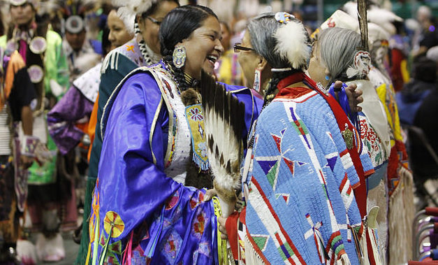 Two old friends in bright traditional dress, greet each other at First Nations Powwow.
