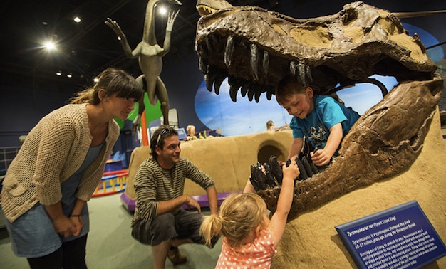 Two children playing on a dinosaur display at the Exploration Place in Prince George, B.C.
