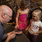 two kids with an adult showing them a tarantula spider at the Exploration Place