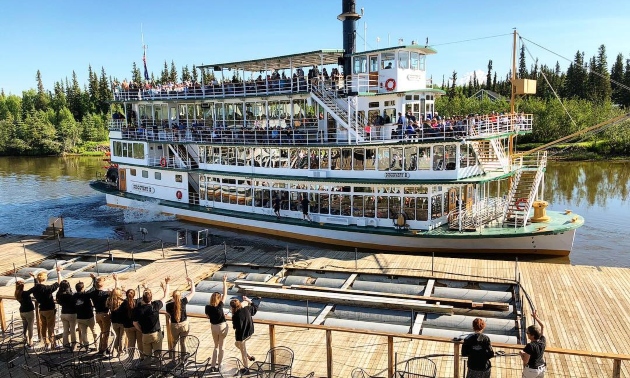 The Discovery III riverboat with people waiting on the shore to get on