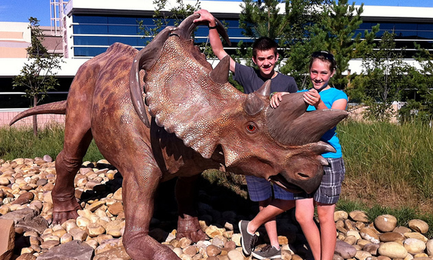 two people standing next to a dinosaur sculpture in Drumheller Alberta