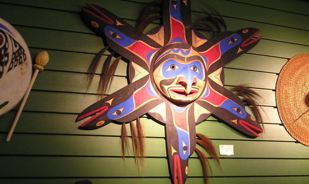 The Sun Mask, a piece by Wilson George, is surrounded by other works of art.
