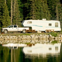 Overlooking a lake to see a truck and 5th wheel, parked in a campspot. 