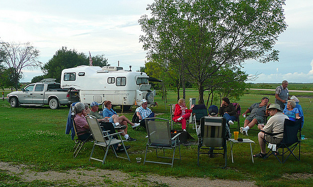 people sitting on lawn chairs beside RVs