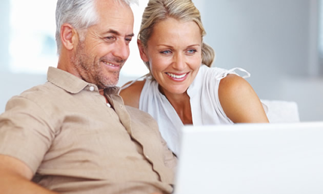 A couple is sitting and using a laptop. 