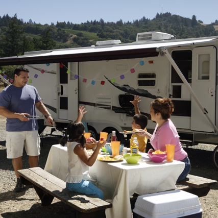 A family eating at a picnic table in front of their RV