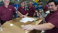 RV Products associates who had a hand in manufacturing the unit are shown with the gold guilded air conditioning unitl in the factory.