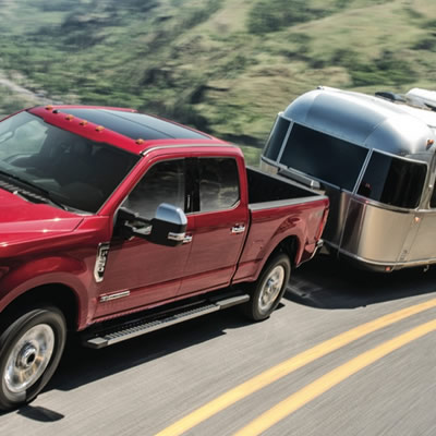 Picture of red Ford truck towing silver Airstream trailer. 