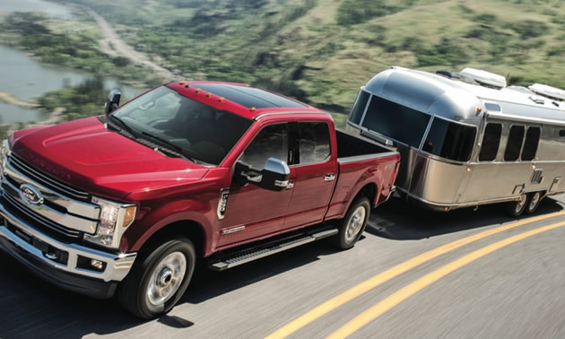 Picture of red Ford truck towing silver Airstream trailer. 