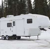 A 5th wheel sitting in the snow. 