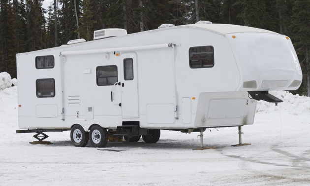 A 5th wheel sitting in the snow. 