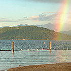 person taking a photo of a rainbow on a beach