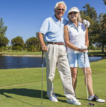 A happy senior couple standing with their clubs on a golf green. 