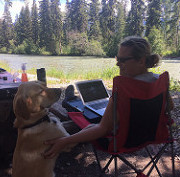 Oetter and Sommerfeld's dog, Kye, looking up at Sommerfeld who is sitting in a lawn chair at Canoe River Campground in Valemount, B.C.