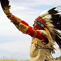 Elderly First Nations man in feather headdress and beaded leather clothing